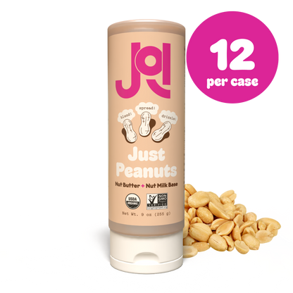 A squeeze tube of Just Peanuts Nut Butter + Nut Milk Base stands upright on a white background with roasted peanuts beside it. A pink circular badge in the top right reads '12 per case'.